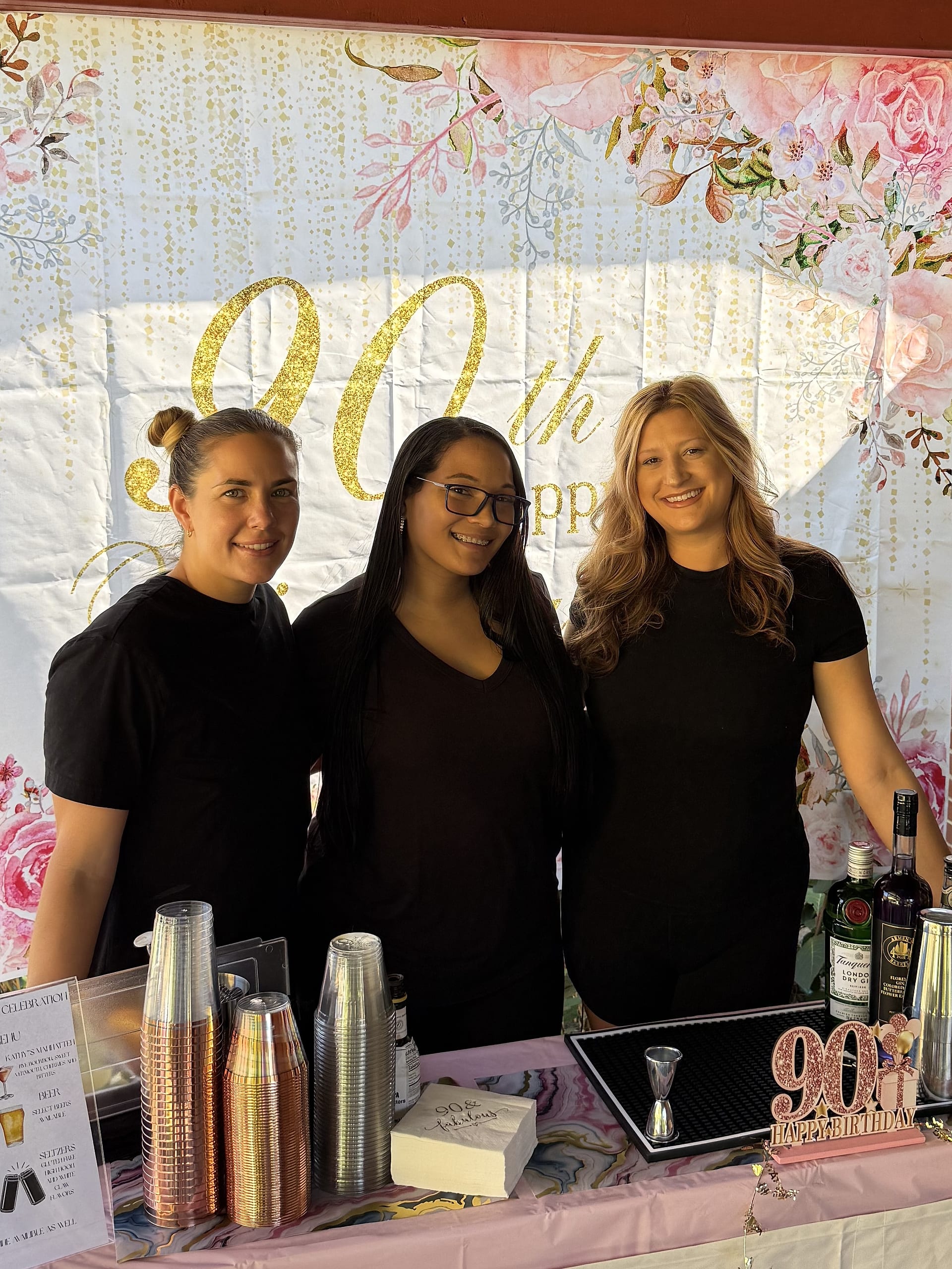The three Tow And Toast bartenders behind their bar at a 90th birthday party
